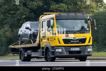 Bicester, Oxon., UK - 8 ottobre 2023: Trasportatore di auto AA. Autocarro stradale adibito al soccorso stradale che guida su una strada di campagna inglese. Foto Stock