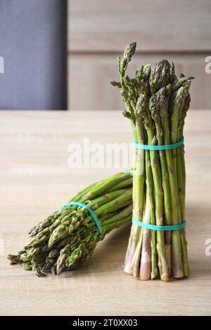 Primo piano di mazzi di asparagi verdi su sfondo di legno Foto Stock