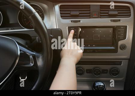 Scelta della radio preferita. Donna che preme il pulsante sull'audio del veicolo in auto, primo piano Foto Stock