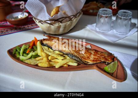 Pesce, patatine fritte e verdure sul piatto serviti nel villaggio peruviano sul lago Titicaca Foto Stock