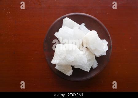 Alluminio, pietre di alluminio trasparenti o alluminio di potassio su piatto, decorate con fiori. Utile per trattamenti estetici e termali. Utilizzare per trattare gli odori del corpo sotto Foto Stock