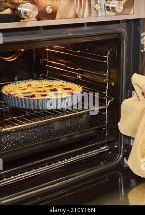 La torta di ciliegia viene cotta in un forno elettrico nella cucina casalinga Foto Stock