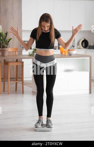 Scioccata bella giovane donna con le squame in cucina. Concetto di perdita di peso Foto Stock