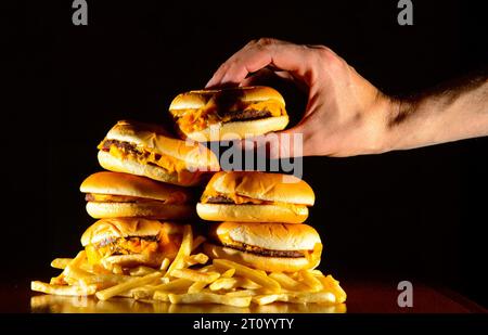 La foto del file datata 09/07/14 di una foto generica mostra una pila di cheeseburger e patatine fritte. Etichettare alcuni alimenti come "coinvolgenti" potrebbe aiutare le persone a cambiare la loro dieta, hanno affermato gli scienziati, poiché le stime suggeriscono che un adulto su sette e un bambino su otto potrebbe essere agganciato a cibi ultra-trasformati (UFP). Data di emissione: Martedì 10 ottobre 2023. Foto Stock