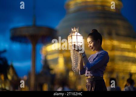 Bellissime donne asiatiche che tengono una tradizionale lanterna di carta durante il festival delle lanterne di Yi peng al Wat Phra That Hariphunchai, provincia di Lamphun, Thailandia. Foto Stock