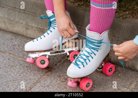 Dettaglio ravvicinato delle mani di uno skater che legano i lacci di un paio di pattini a rulli quadrupli. Foto Stock