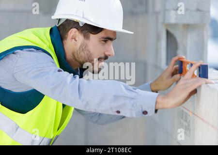 L'uomo muratore è livello di misurazione Foto Stock