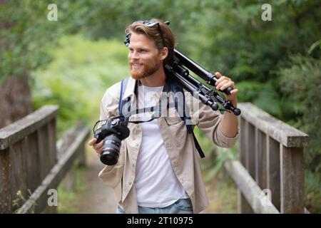 fotografo maschio sul posto con treppiede sulla spalla Foto Stock