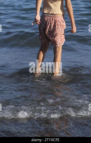 ragazza che salta sulla riva giocando tranquillamente in autunno Foto Stock