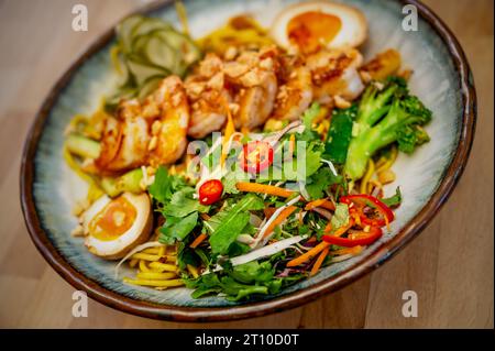 Insalata agrodolce, uova sode e gamberi con peperoncino sul piatto, primo piano. Foto Stock