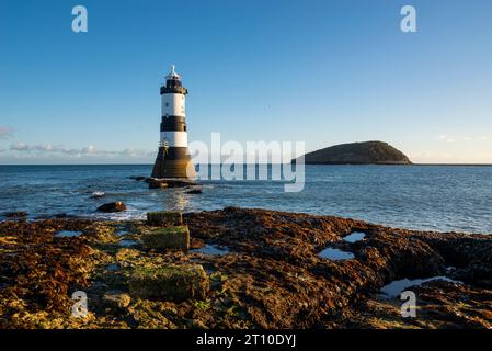 Penmon Point sulla costa di Anglesey, Galles del Nord. Faro di Trwyn Du con Puffin Island alle spalle. Foto Stock