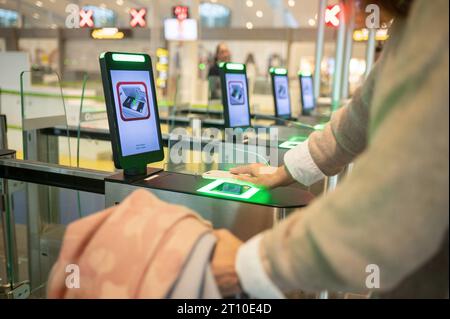 Ritaglia la donna utilizzando lo smartphone durante la scansione delle informazioni nel pass Smart Gate in aeroporto Foto Stock