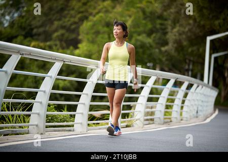 giovane donna asiatica jogger che cammina rilassandosi riposando nel parco cittadino Foto Stock