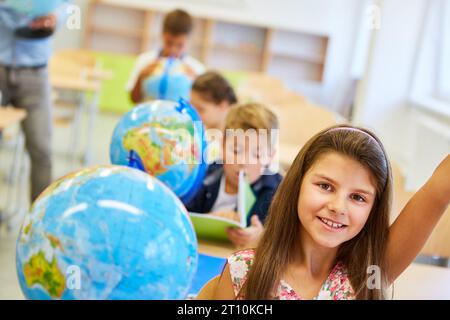 Ritratto di una studentessa sorridente per globo in classe di geografia Foto Stock