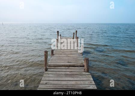 Molo o molo in legno sul lago in un'atmosfera nebbiosa. Foto Stock