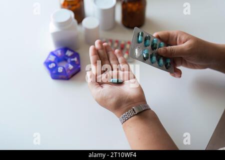 Donne che organizzano il suo farmaco in un dispenser di pillole. donna che prende pillole dalla scatola. Sanità e concetto con i farmaci. Medicinali sul tavolo Foto Stock