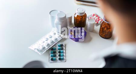 Donne che organizzano il suo farmaco in un dispenser di pillole. donna che prende pillole dalla scatola. Sanità e concetto con i farmaci. Medicinali sul tavolo Foto Stock