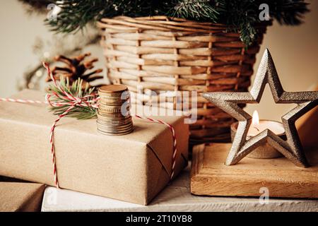 Concetto di bilancio e finanze natalizie. Pila di monete monetarie contro l'albero di Natale e ornamenti in casa. Foto Stock