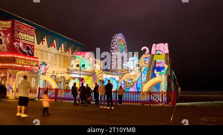 Castello rimbalzante per bambini e ruota panoramica del molo centrale di notte Foto Stock