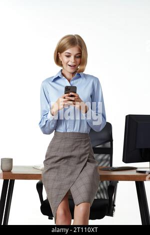 donna d'affari bionda che usa il telefono in ufficio Foto Stock