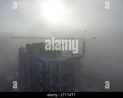 gru a torre su un cantiere con vista aerea densa nebbia al mattino Foto Stock