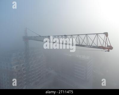 gru a torre su un cantiere con vista aerea densa nebbia al mattino Foto Stock