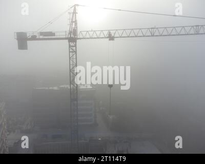 gru a torre su un cantiere con vista aerea densa nebbia al mattino Foto Stock