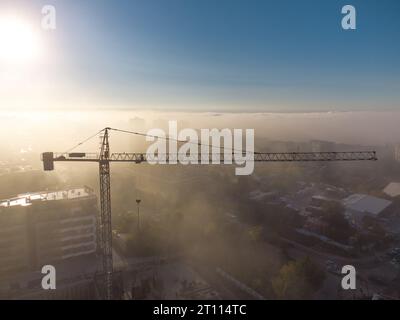 gru a torre su un cantiere con vista aerea densa nebbia al mattino Foto Stock