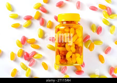 Vitamine gommose e supplemento per adulti. La donna mangia gelatina dolce multivitaminica caramelle microelementi da pillole trasparenti bottiglia, farmaci moderni e. Foto Stock