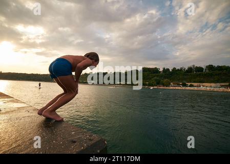 il bambino di 8 anni si tuffa in mare da un molo. Caldo giorno d'estate. Foto Stock