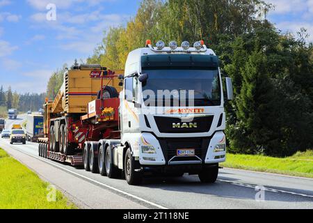 Il dumper MAN TGX 33,580 trasporta la gru SevenLift su un rimorchio con pianale ribassato come carico eccezionale, segue un'auto di scorta. Raasepori, Finlandia. 22 settembre 2023. Foto Stock