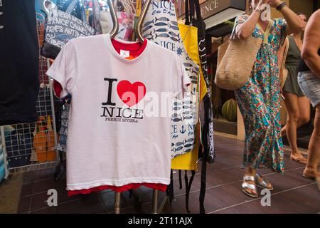 T-shirt/T-shirt "i Love Nice" appesa su un espositore su marciapiede, con logo a forma di cuore, in vendita in un negozio di souvenir turistico a Nizza, Francia. (135) Foto Stock