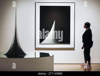 Londra, Regno Unito. 10 ottobre 2023. Il personale posa con superficie di rivoluzione con curvatura negativa costante, 2006 (primo piano) e un'immagine nella serie forme concettuali/forme matematiche:superfici, 2004 (sfondo) nell'anteprima. Anteprima della mostra "Hiroshi Sugimoto: Time Machine" e foto alla Hayward Gallery. La mostra si svolgerà fino al 7 gennaio 2024. Crediti: Imageplotter/Alamy Live News Foto Stock