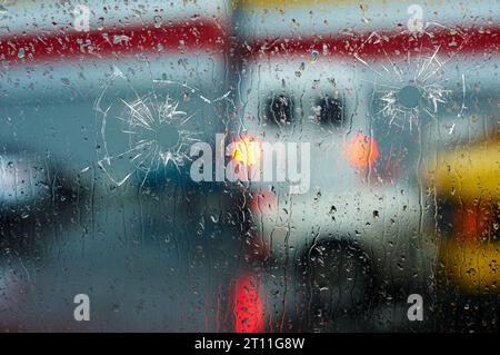 fori di proiettile in vetro sullo sfondo di una città sfocata da vicino Foto Stock