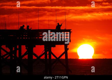 Isola di Palms, Stati Uniti. 10 ottobre 2023. Il folklore dei pescatori si staglia all'alba mentre scendono per la mattina al largo del molo Sea Cabins in una mattinata fredda nella bassa campagna, il 10 ottobre 2023 a Isle of Palms, South Carolina. Crediti: Richard Ellis/Richard Ellis/Alamy Live News Foto Stock