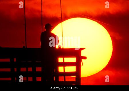 Isola di Palms, Stati Uniti. 10 ottobre 2023. Il folklore dei pescatori si staglia all'alba mentre scendono per la mattina al largo del molo Sea Cabins in una mattinata fredda nella bassa campagna, il 10 ottobre 2023 a Isle of Palms, South Carolina. Crediti: Richard Ellis/Richard Ellis/Alamy Live News Foto Stock