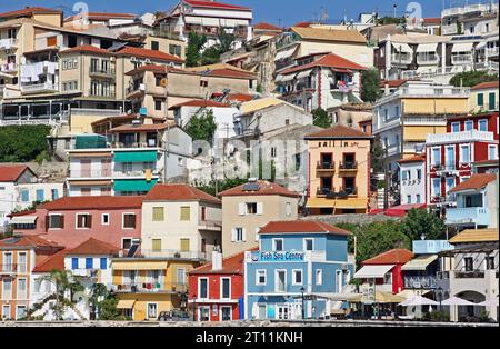 Colorate case e ristoranti sulla scogliera si affacciano sul pittoresco lungomare di Parga, una cittadina costiera nella regione dell'Epiro, nel nord-ovest della Grecia continentale Foto Stock