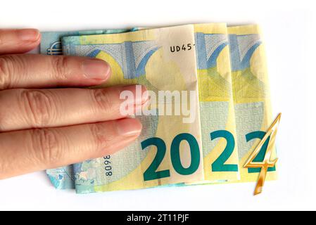 2024 scritto con banconote in euro in una mano isolato su sfondo bianco, auguri di capodanno concetto di denaro Foto Stock