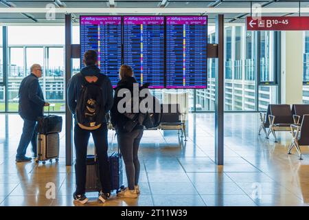 BERLINO, GERMANIA - 9 OTTOBRE 2023: Giovani coppie al display informazioni sulla partenza alla ricerca del loro volo. Foto Stock