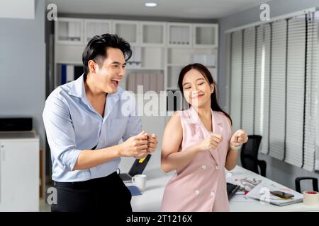 Felicissimo uomo d'affari e donna d'affari asiatica sorridendo e ballando con felicità e celebrando il successo in ufficio. - Un posto di lavoro di successo e divertente Foto Stock