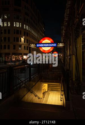 Londra, Regno Unito: Ingresso alla stazione della metropolitana Monument di notte con il cartello illuminato della metropolitana di Londra. Foto Stock