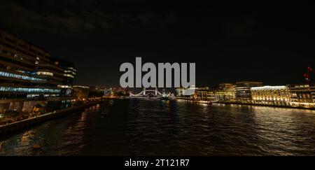Londra, Regno Unito: Vista notturna sul Tamigi dal London Bridge verso un Tower Bridge aperto. Panorama grandangolare. Foto Stock