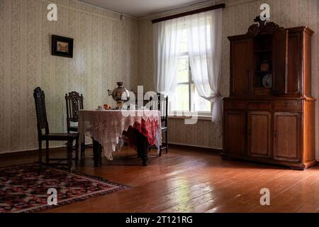 Interno originale di una sala da pranzo in una casa rurale con un buffet, un tavolo con una tovaglia e un samovar. Foto Stock