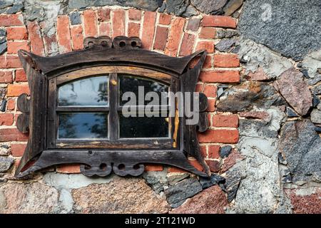 Finestra in legno in una cornice di mattoni su un muro di pietra. Dalla serie Window of the World. Foto Stock