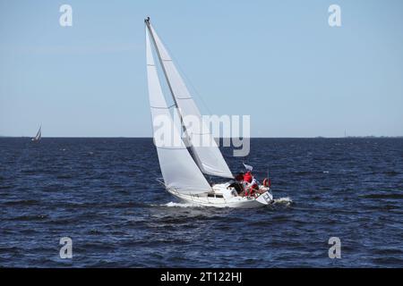 yacht a vela con un equipaggio con vele rialzate, uno yacht in movimento in mare aperto, le vele sono piene di vento, lo yacht taglia l'onda Foto Stock