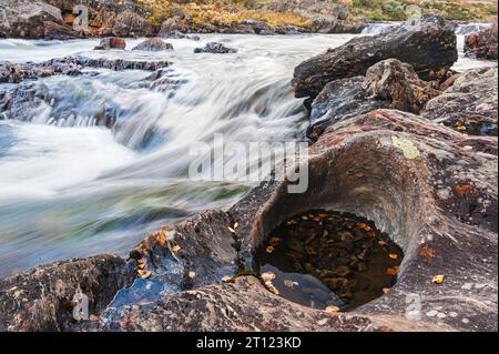 Il rapido fiume scorre sulle rocce attraverso il paesaggio norvegese autunnale. Foto Stock