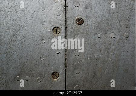 Sfondo metallico con rivetti e viti. Frammento di una vecchia fusoliera dell'aereo. Foto Stock