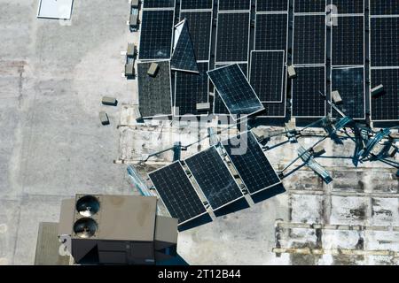 Vista dall'alto dei pannelli solari fotovoltaici distrutti dall'uragano Ian montati sul tetto di un edificio industriale per la produzione di elettricità ecologica verde Foto Stock