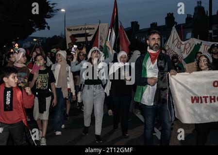 Dublino, Irlanda. 10 ottobre 2023. Una folla di manifestanti marcia verso l'ambasciata israeliana durante la manifestazione. Centinaia di persone si sono riunite ieri sera di fronte al Dáil Éireann a Dublino per manifestare solidarietà al popolo palestinese. I manifestanti marciarono verso l'ambasciata israeliana. I manifestanti hanno affermato che il governo irlandese ha tagliato i legami diplomatici con Israele e incoraggiato l'UE a fare lo stesso alla luce del recente attacco israeliano a Gaza, che ha ucciso centinaia di palestinesi. Credito: SOPA Images Limited/Alamy Live News Foto Stock