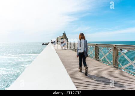 Una giovane donna che passeggia insieme lungo il ponte di legno a Plage du Port Vieux a Biarritz, in vacanza nel sud-est della Francia. Biarritz, dipartimento Foto Stock